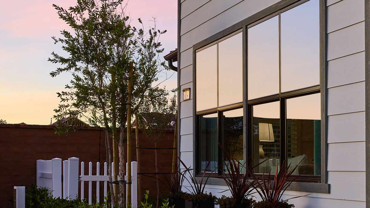 Home exterior with sunset reflecting in LULA single hung windows with simulated divided lites.